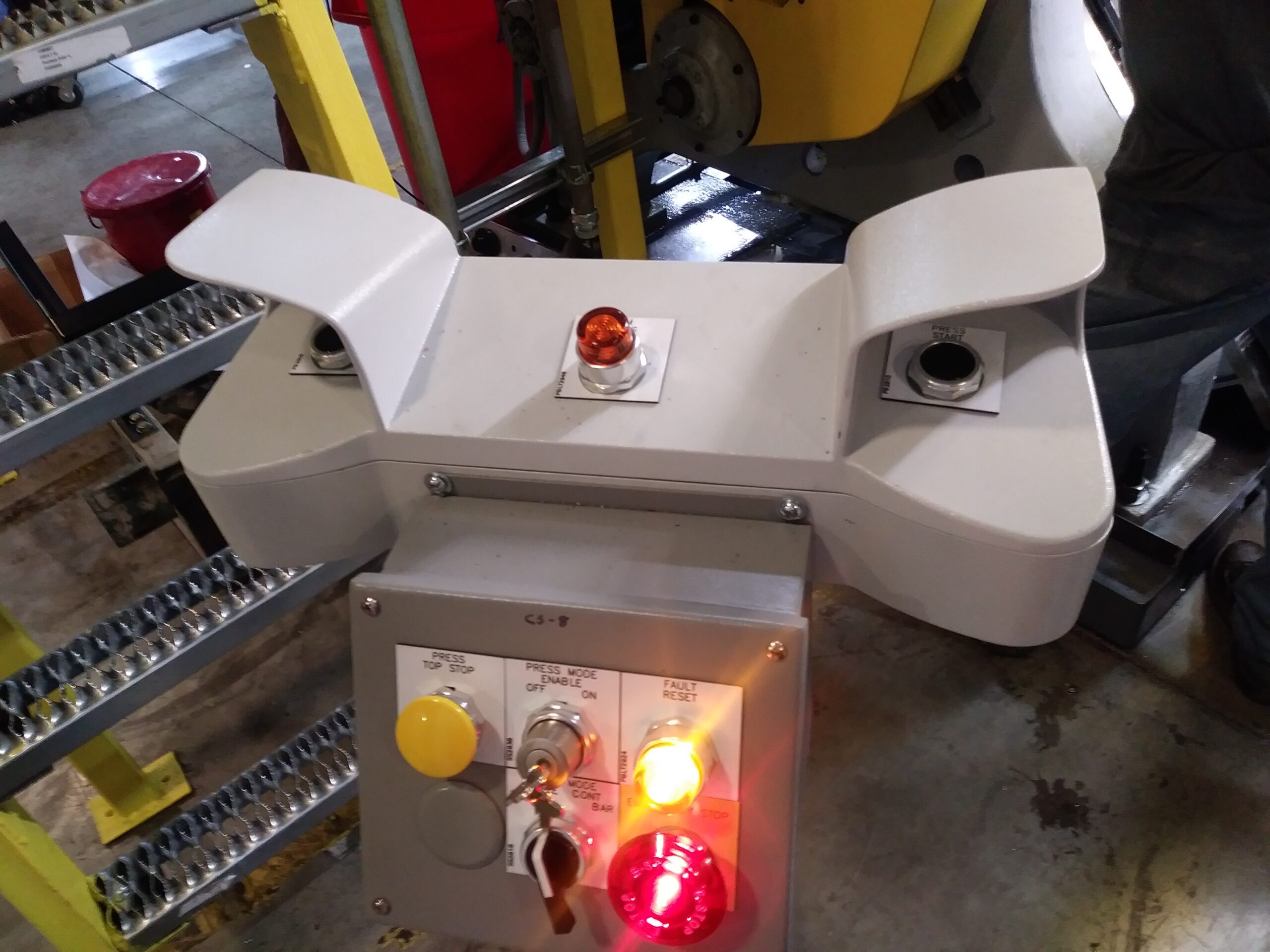 Ergonomic industrial two-hand control station with palm buttons, emergency stop, and keyed mode selector for power press safety.