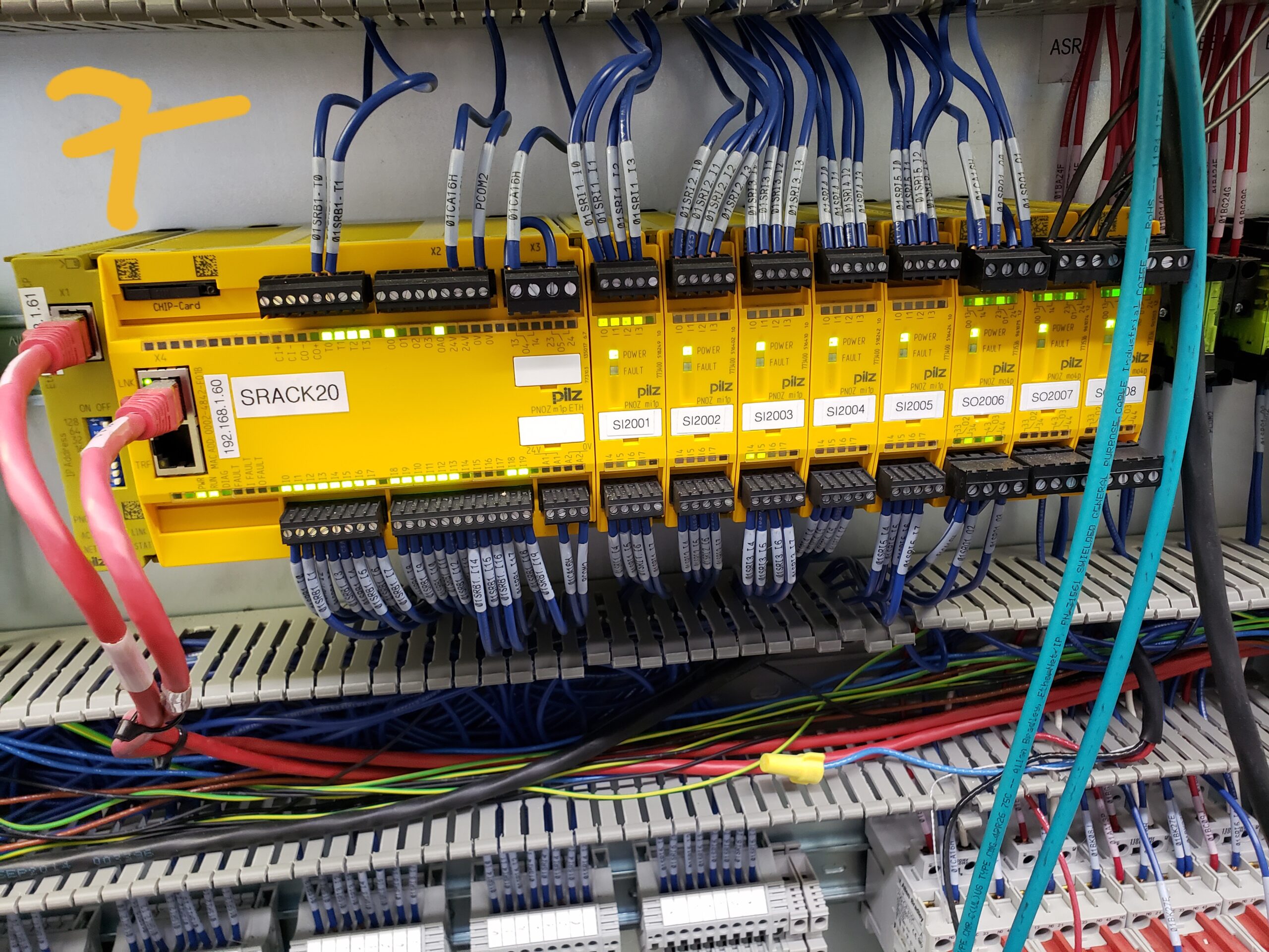 Industrial control panel with safety relay modules and a safety controller wired to monitor emergency stops, interlocks, and safeguarding devices.
